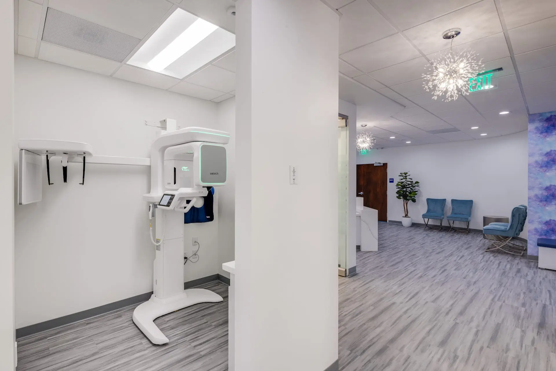 Stellar Orthodontics in San Marcos, CA features a modern dental office equipped with a panoramic X-ray machine and a stylish waiting area with blue chairs and decorative lighting.